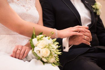 Billede af brudepar der sidder i kirken og holder i hånden